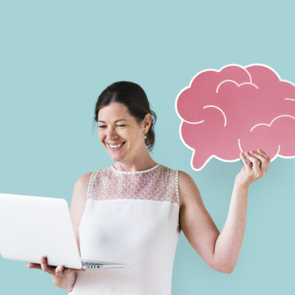 Woman holding a brain icon and using a laptop